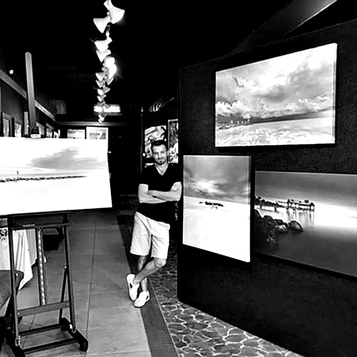 Portrait of landscape photographer Alexandr Popovsky with his seascape prints